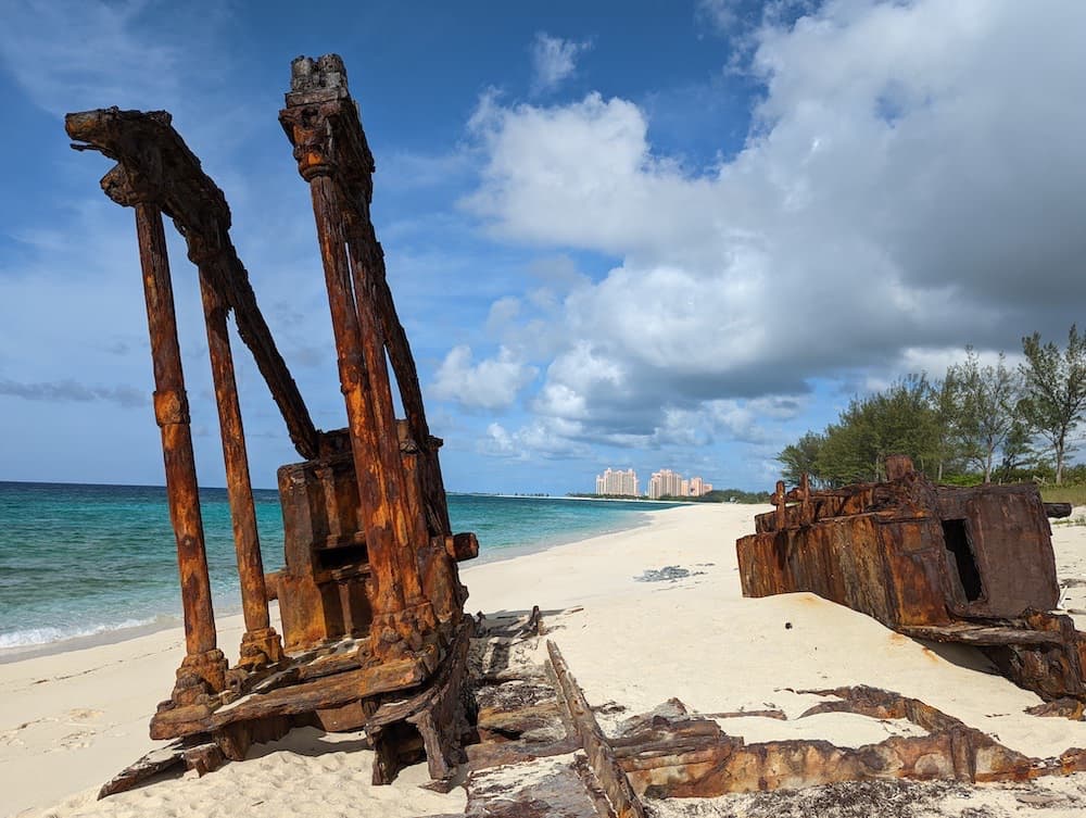 Rusty machinery on the beach Paradise Island, Nassau with Atlantis Resort in background. Turquoise water, sandy beach, puffy white clouds.